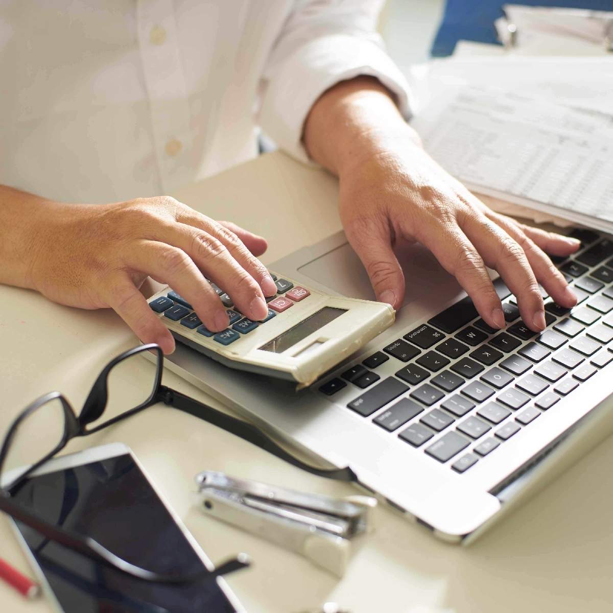 man working with calculator and laptop
