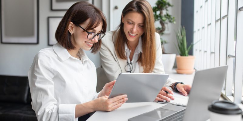 two women sharing tablet in office